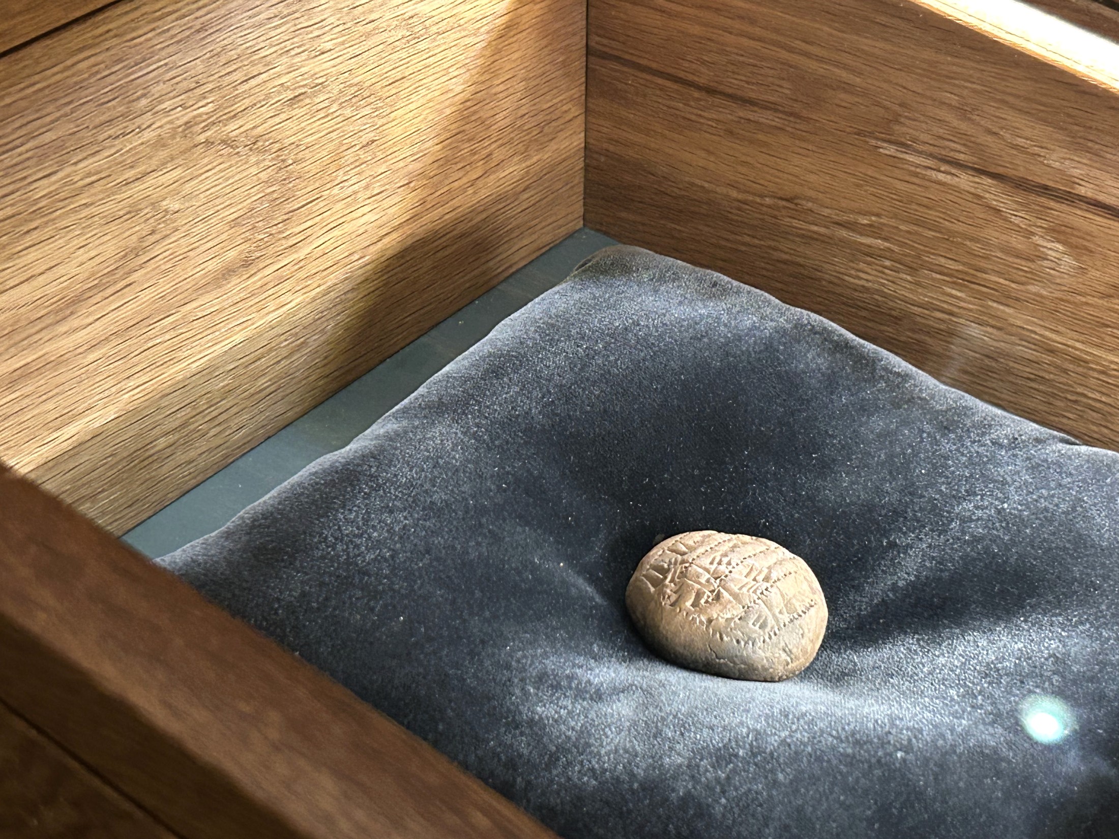 Detalj av en trämonter med mörk, mjuk inredning och en liten sten.