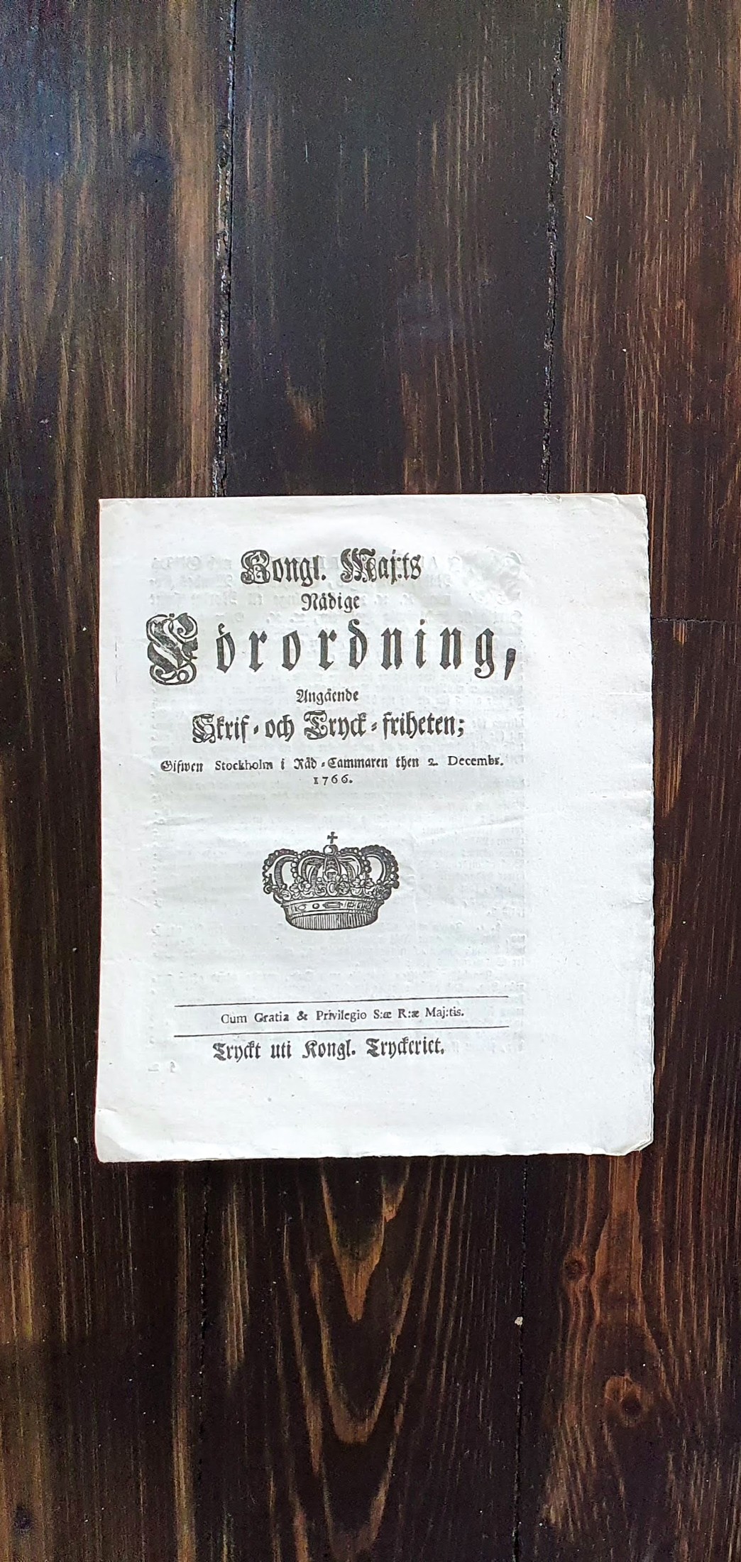 Ett historiskt tryck placerat på en mörk träyta.